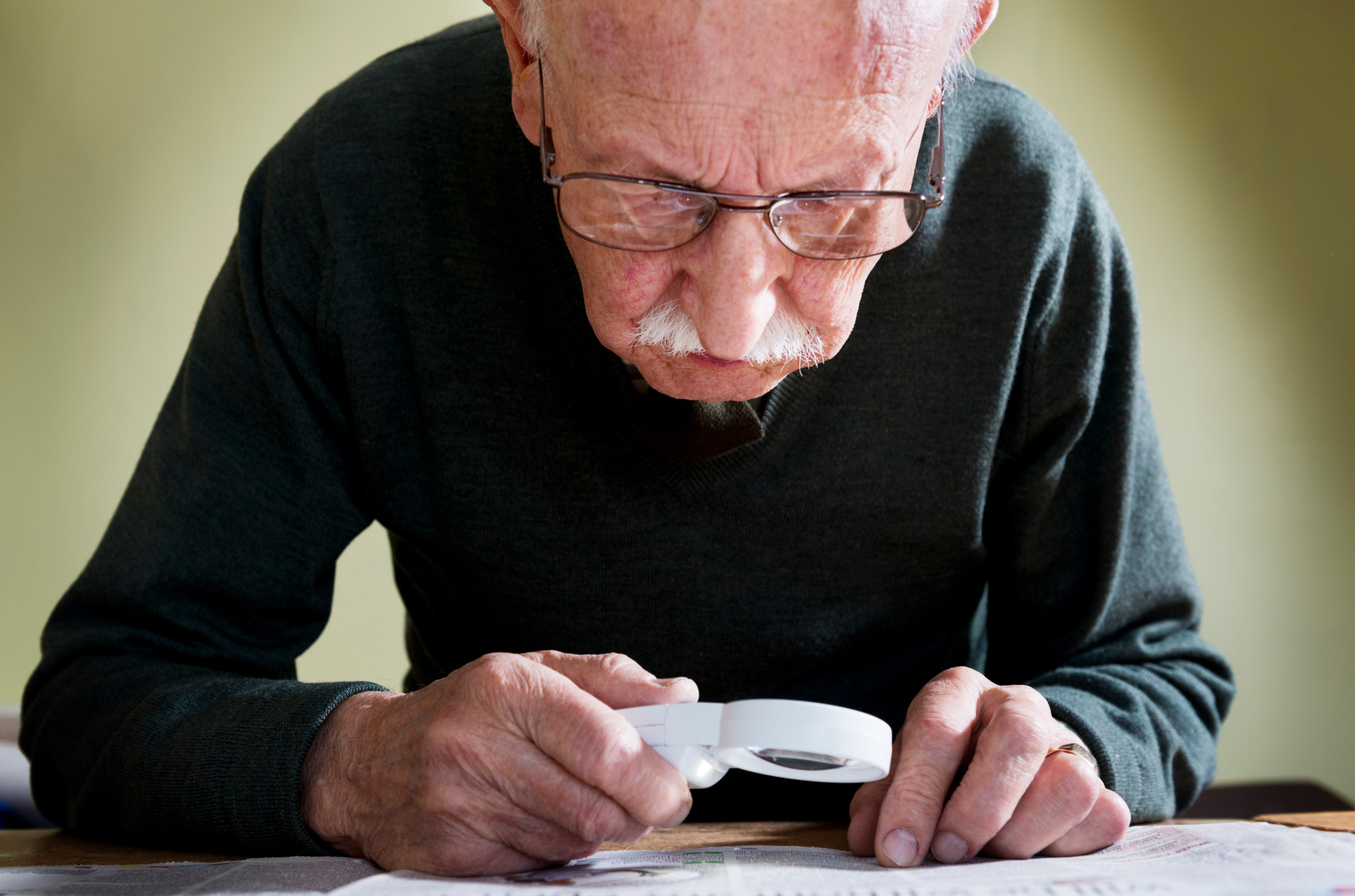 A senior man using a magnifying glass