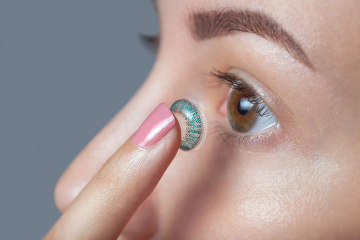 Close up of a young woman inserting a coloured contact lense