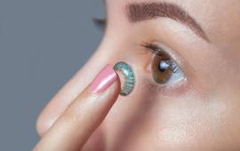 Close up of a young woman inserting a coloured contact lense