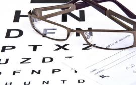 glasses on top of prescription pad and Snellen chart