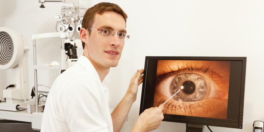 Young male optometrist looking a an eye on a screen