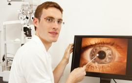 Young male optometrist looking a an eye on a screen