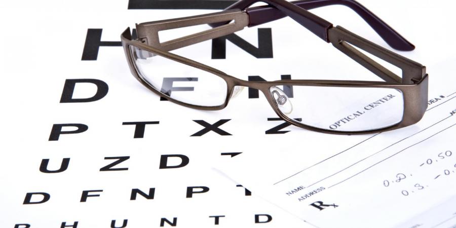 glasses on top of prescription pad and Snellen chart